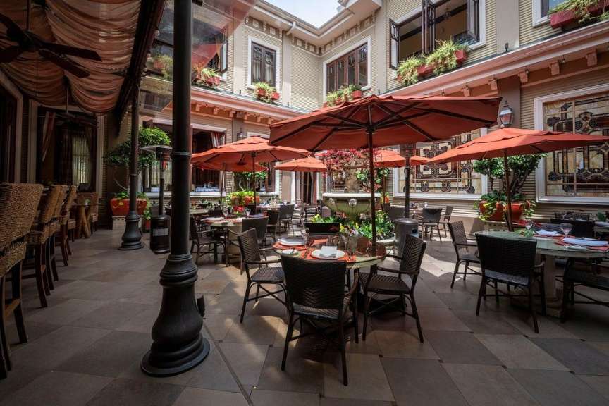 Der Innenhof eines Restaurants ist mit Tischen, Stühlen und Sonnenschirmen eingerichtet.
