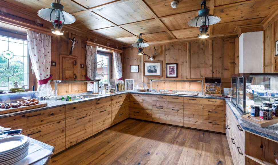 Rustikales Holzbuffet mit Frühstücksartikeln, Kaffeetassen und traditioneller Beleuchtung in einem gemütlichen Speisesaal.