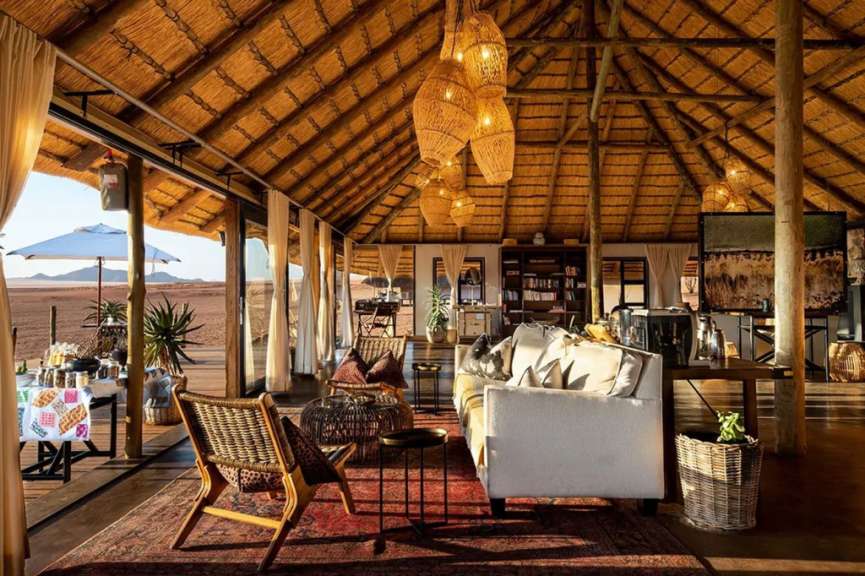 Ein luxuriöses Safari-Lodge mit Strohdach und Blick auf die Wüste.