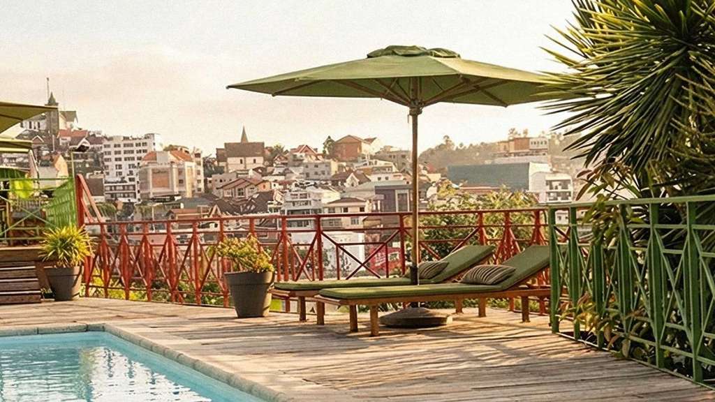 Blick von der Holzterrasse mit Pool und Liegen auf die Stadt Antananarivo.