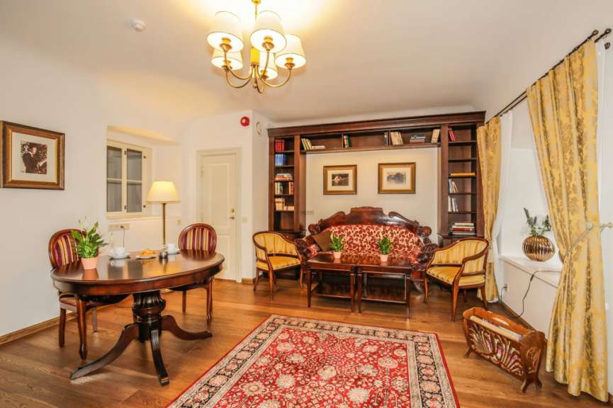 Elegante Lobby-Lounge in Estland mit Holztischen, roten Sesseln, Bücherregalen, Teppich und Kronleuchter.