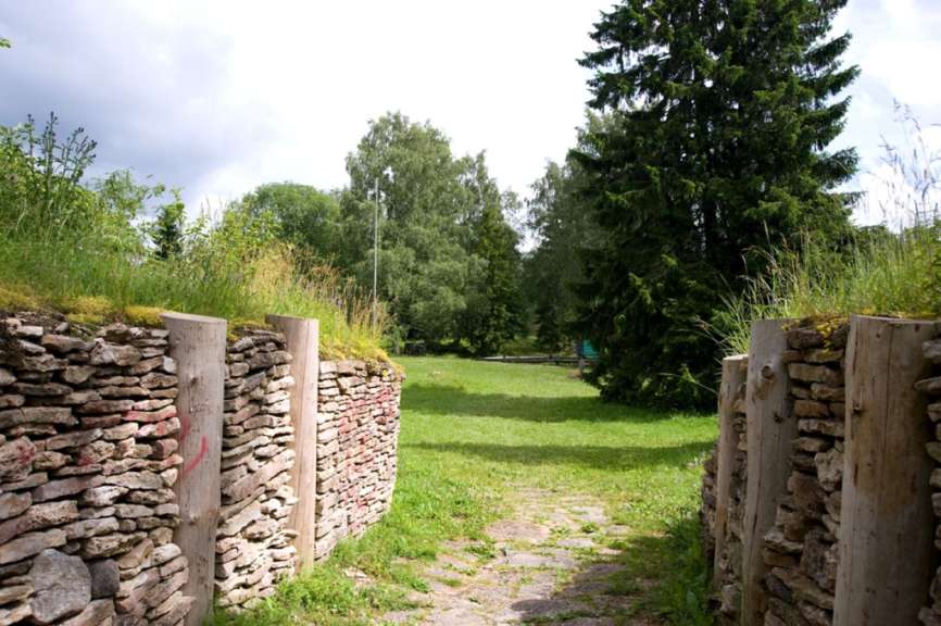 Ein bewaldetes Gelände in Estland mit restaurierten Steinmauern und Holzbalken der historischen Burg Varbola.