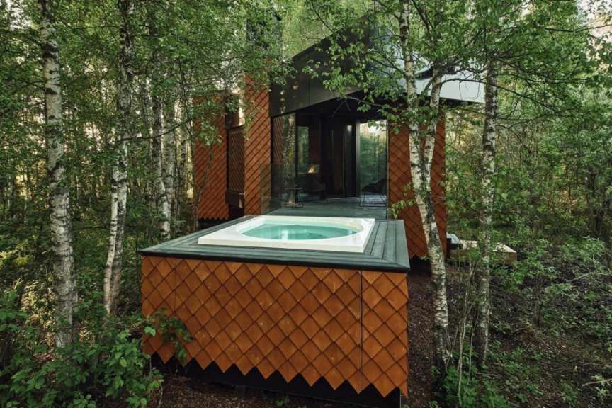 Eine moderne Villa mit Terrasse und Whirlpool liegt eingebettet in einen dichten Wald in Estland.