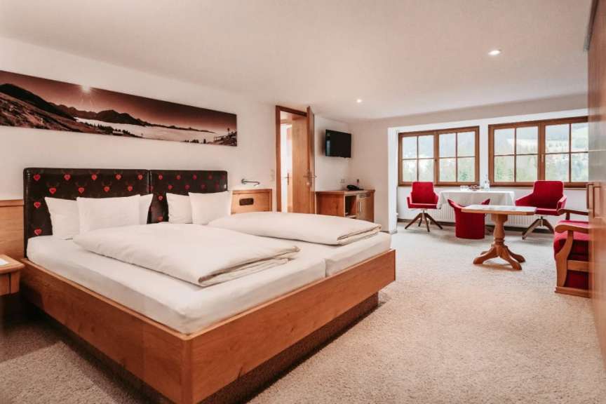 Zimmerbeispiel in einem österreichischen Hotel mit großem Doppelbett, Sitzecke und Panoramafenster.