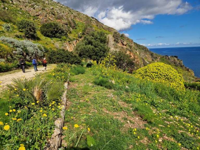 Wanderer auf einem Küstenweg in einer bergigen Landschaft in Italien.