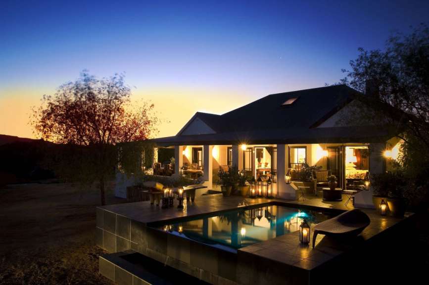 Ein Haus mit einem Pool und einer Veranda bei Sonnenuntergang