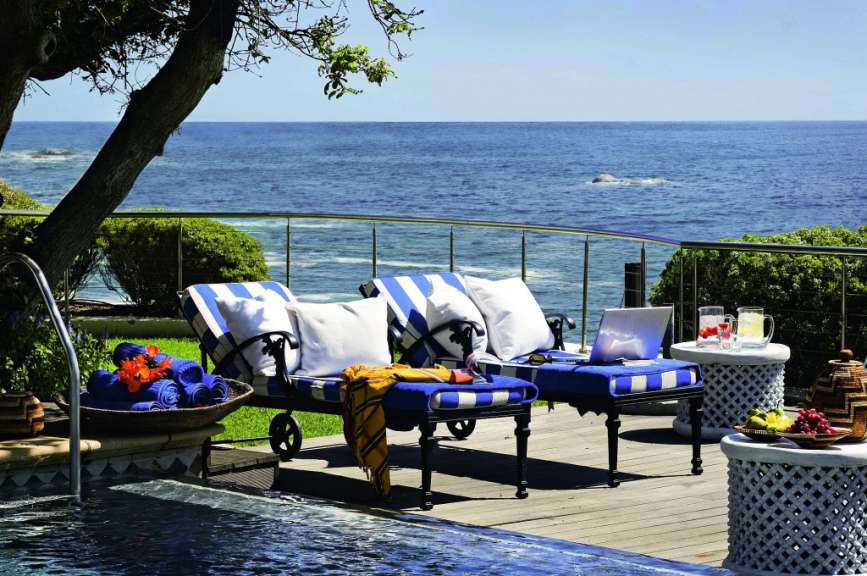 Liegestühle neben einem Pool mit Blick auf das Meer
