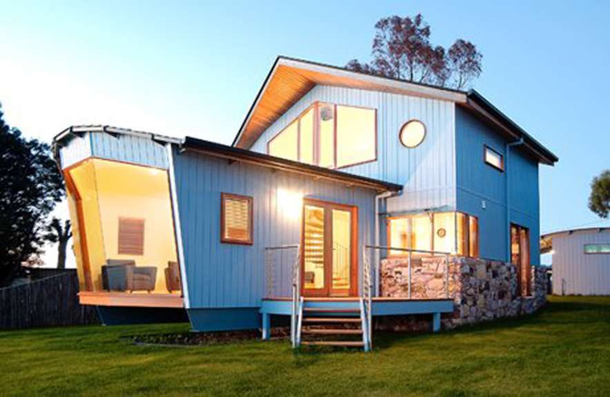 Ein blaues und weißes Haus mit vielen Fenstern und einem Deck .
