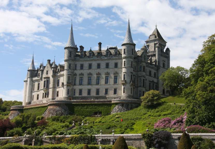 Ein großes Schloss sitzt auf einem Hügel inmitten von Bäumen