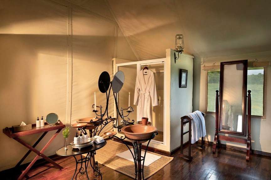 Ein luxuriöses Badezimmer mit zwei Waschbecken, einem begehbaren Kleiderschrank, einem Spiegel und einem Handtuchhalter in einem Zelt.