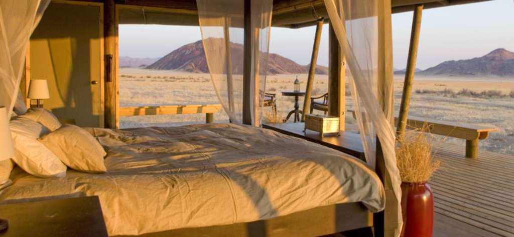 Ein Schlafzimmer mit Himmelbett und Blick auf die Wüste