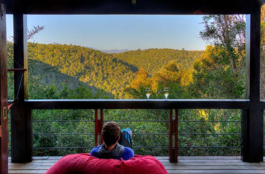 Ein Mann sitzt auf einem Balkon mit Blick auf einen Wald