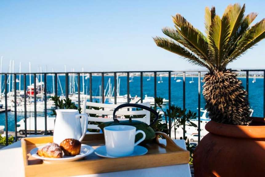 Ein Tablett mit Kaffee und Croissants auf einem Balkon mit Blick auf das Meer