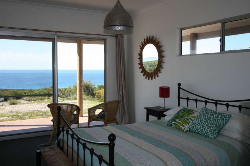 Ein Schlafzimmer mit einem Bett und einem Stuhl mit Blick auf das Meer