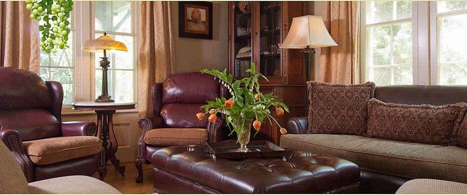 Ein Wohnzimmer mit einem Couchtisch, Stühlen, Lampen und einer Vase mit Blumen .