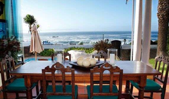Ein Esszimmer mit einem Tisch und Stühlen mit Blick auf das Meer .