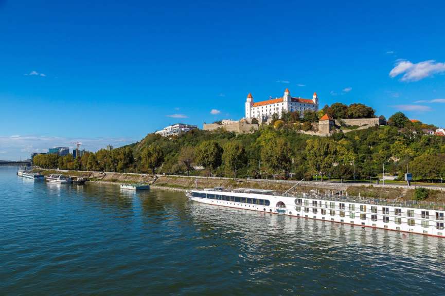 Ein weißes Boot fährt auf einem Fluss in der Nähe eines Schlosses