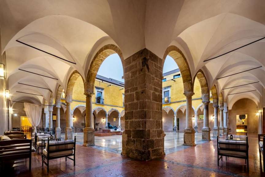 Ein Gebäude mit vielen Steinbögen und Stühlen