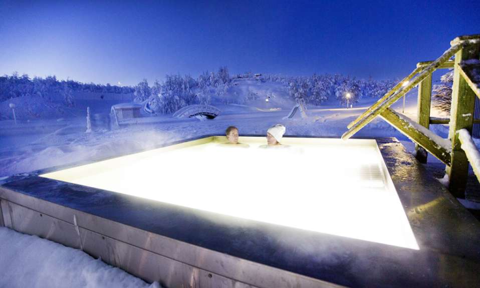 Eine Frau und ein Mann sitzen in einem Whirlpool im Schnee