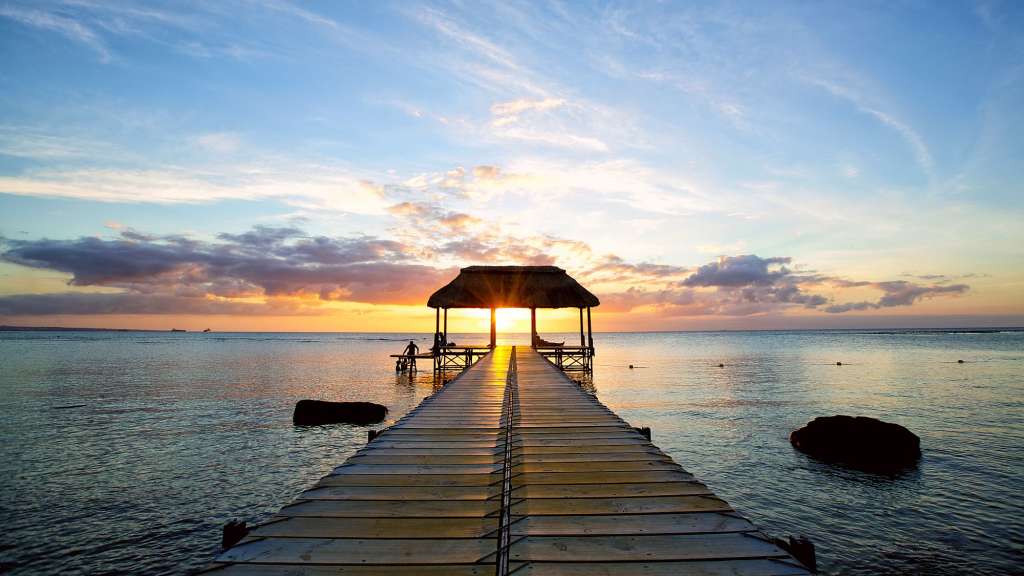 Ein Pier mit einem Strohdach führt ins Meer