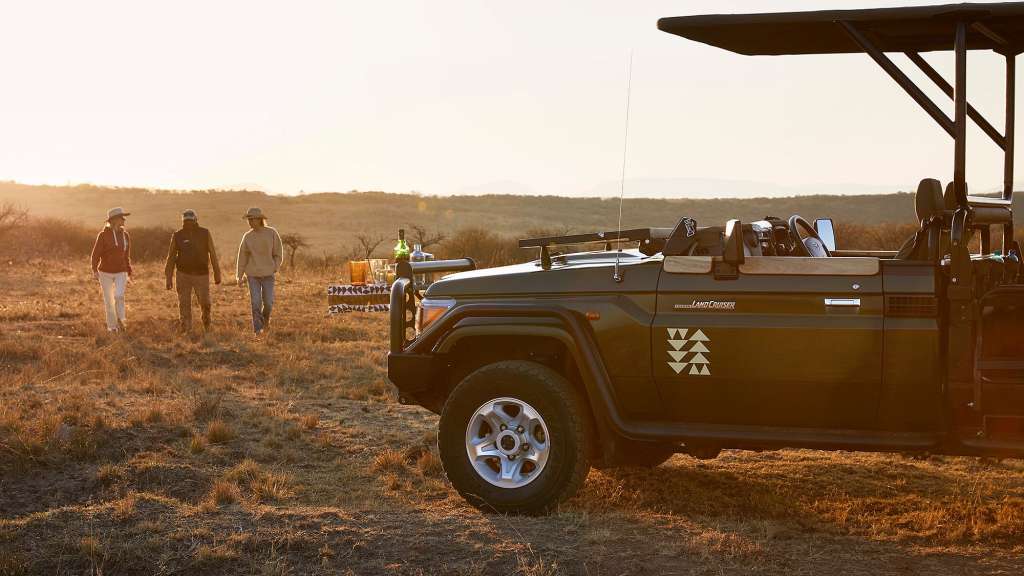 Eine Gruppe von Menschen geht neben einem schwarzen Landcruiser