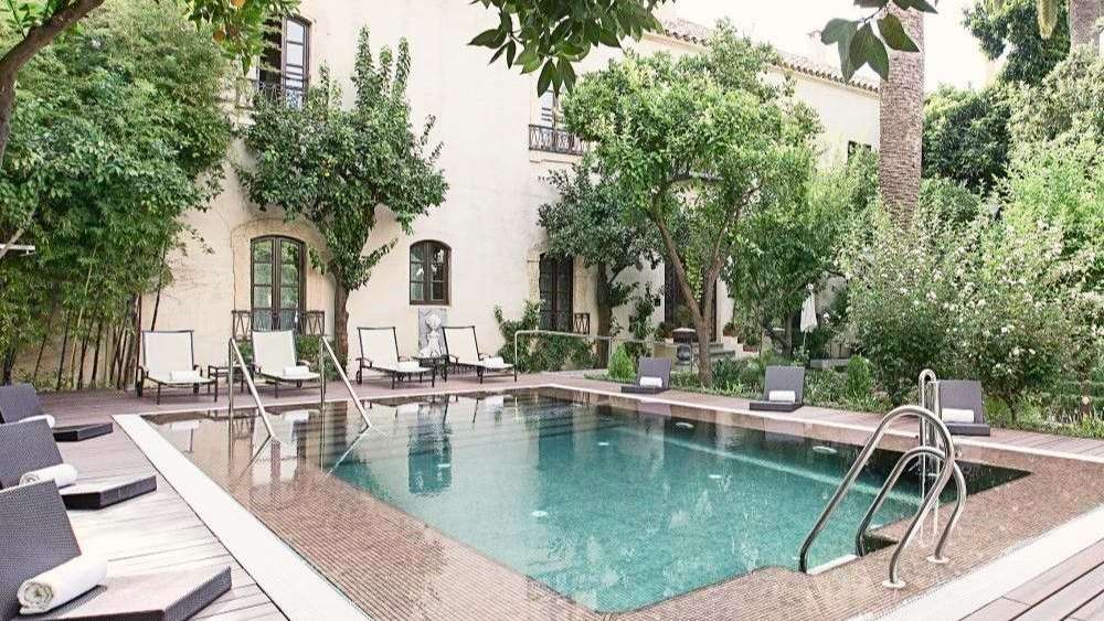 Ein großer Swimmingpool in der Nähe eines weißen Gebäudes /media/cache/w1024-h576-c1024x576/11038407.jpg.webp