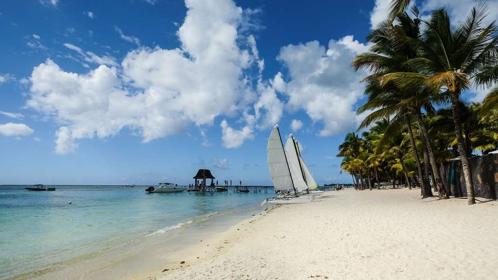 Ein weißes Segelboot sitzt auf einem weißen Sandstrand
