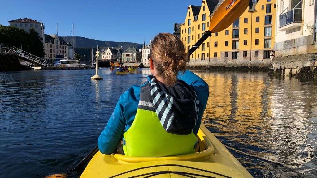 Eine Frau paddelt in einem gelben Kajak mit einem gelben Paddel mit der Aufschrift ' kayak ' darauf