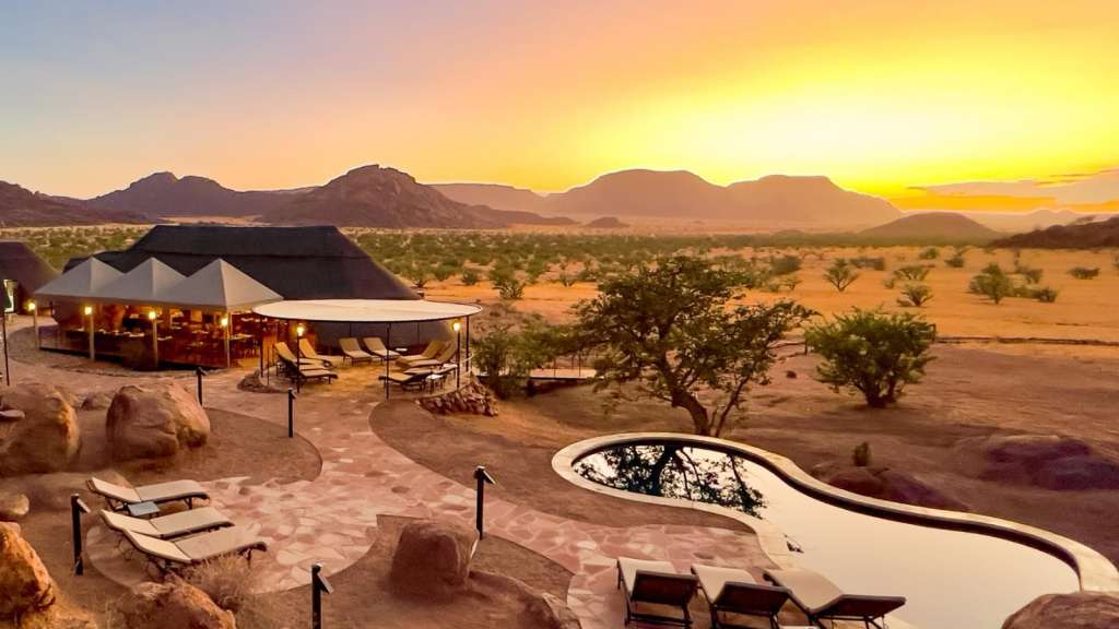 Sonnenuntergang über einem Pool und einem Zelt in der Wüste