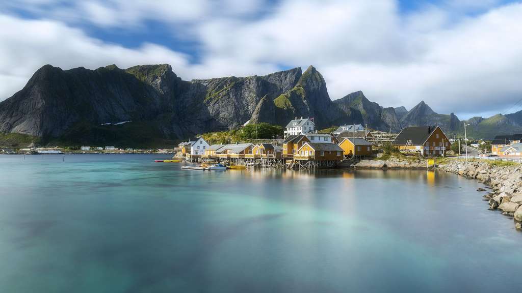 Ein kleines Dorf in der Nähe eines Gewässers mit Bergen im Hintergrund