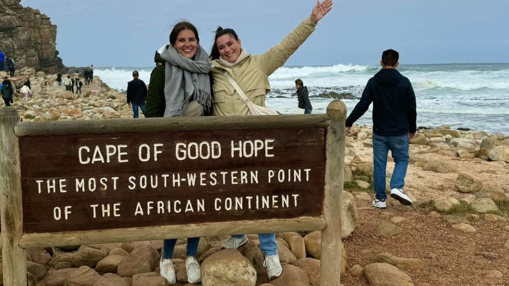 Zwei Frauen stehen neben einem Schild mit der Aufschrift Cape of good hope