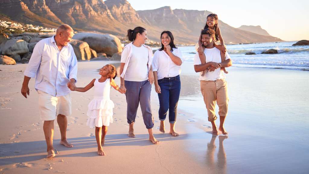 Eine Familie geht am Strand spazieren und hält sich an den Händen