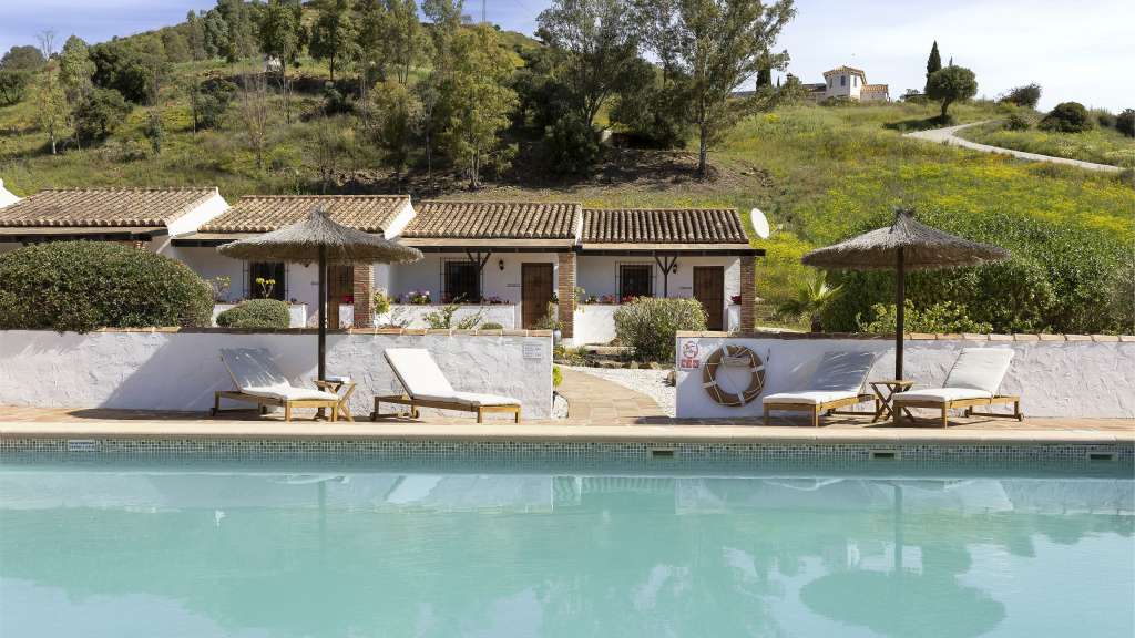 Beschauliches Bergidyll: Gästehaus in Álora Ein Pool mit Liegestühlen und Sonnenschirmen vor einem Haus /media/cache/w1024-h576-c1024x576/11119120.jpg.webp