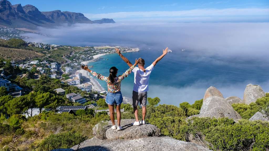 Ein Mann und eine Frau stehen auf einem Felsen mit ihren Armen in der Luft