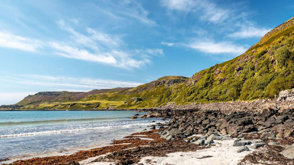 Ein Strand mit einem felsigen Hügel im Hintergrund