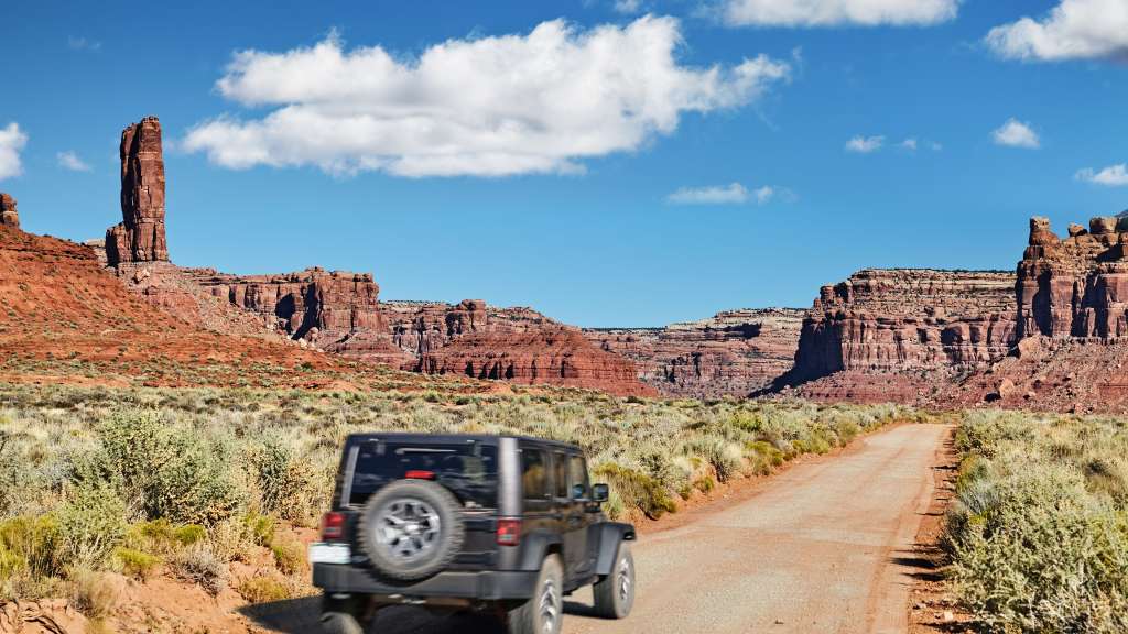 Ein jeep fährt auf einer unbefestigten straße durch die wüste