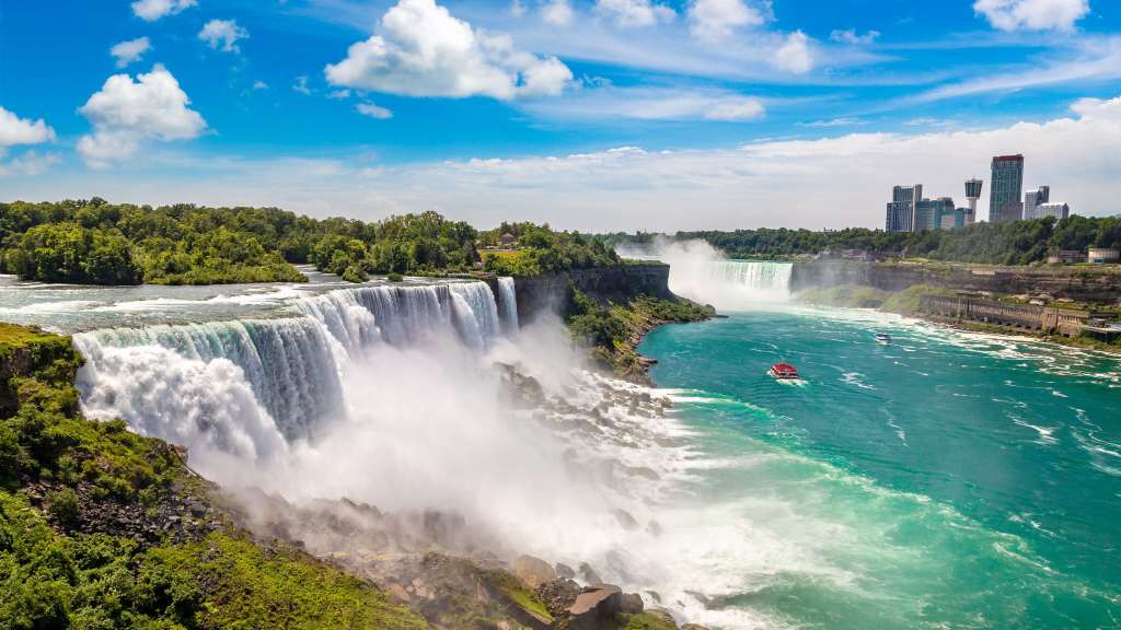 Ein Boot fährt an einem Wasserfall vorbei