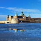 Ein großes Schloss sitzt über einem zugefrorenen See
