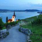 Eine kleine weiße Kirche steht auf einem Hügel mit Blick auf einen See