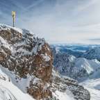 Ein goldenes Kreuz sitzt auf einem schneebedeckten Berg
