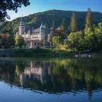 Ein großes Schloss sitzt auf einem Hügel über einem See