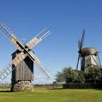 Zwei Windmühlen stehen auf einem grünen Feld