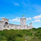 Eine schwedische Flagge fliegt über einer Burgmauer