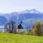 Eine Kirche steht auf einem Hügel mit Blick auf einen See mit Bergen im Hintergrund