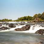 Ein Wasserfall in einem Fluss mit Bäumen im Hintergrund
