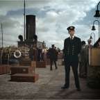 Ein Mann in Uniform steht vor einem Schiff