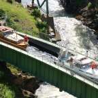 Ein Boot fährt auf einer grünen Brücke über einen Fluss