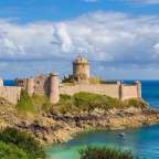 Ein großes mittelalterliches Schloss sitzt auf einer Klippe über dem Ozean