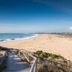 Eine Holztreppe führt hinunter zu einem Strand