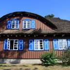 Ein braunes Haus mit blauen Fensterläden und einem strohdach